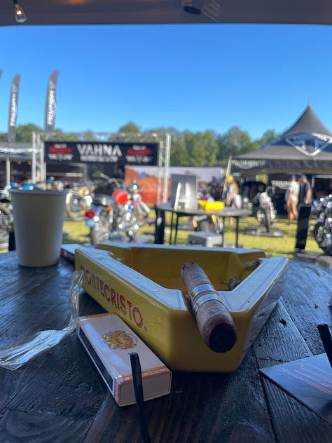 an artist doing a large live sketch of a concept bike; the race track; vintage bikes, and a cigar
