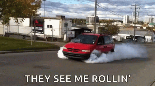 a red van is driving down a street with the words they see me rollin
