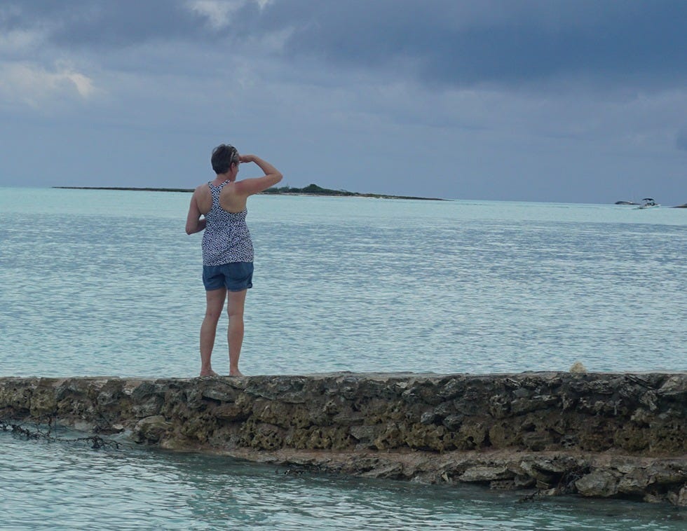 Midlife woman looks at the horizon over the Carribean ocean under stormy skies