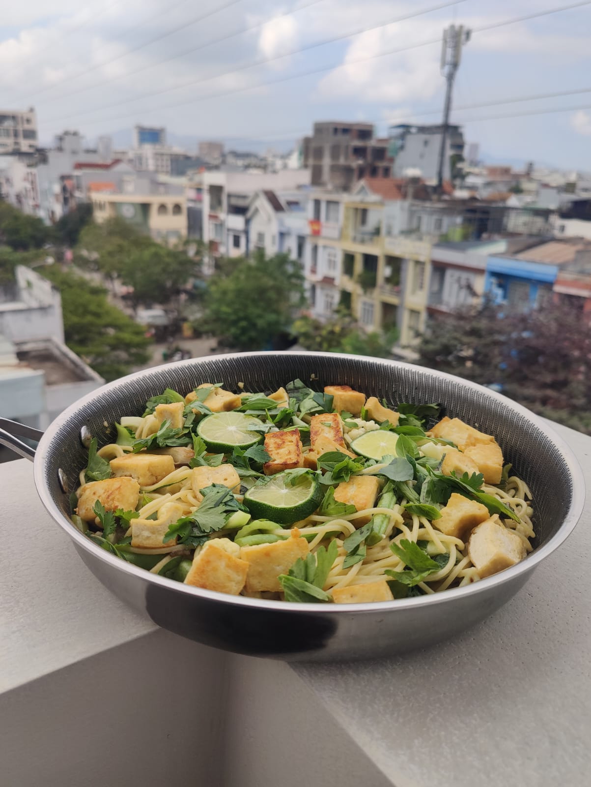 pan of green curry spaghetti on a rooftop
