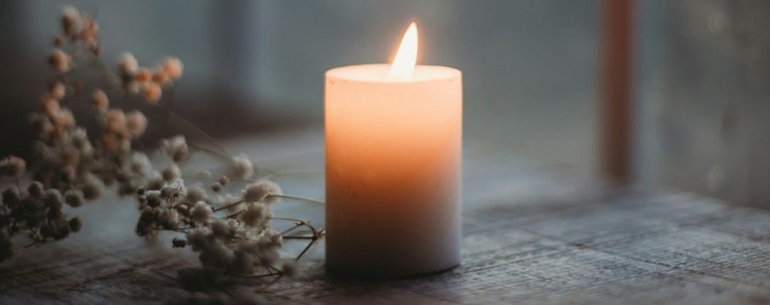 a lit candle sitting on top of a wooden table a lit candle sitting on top of a wooden table