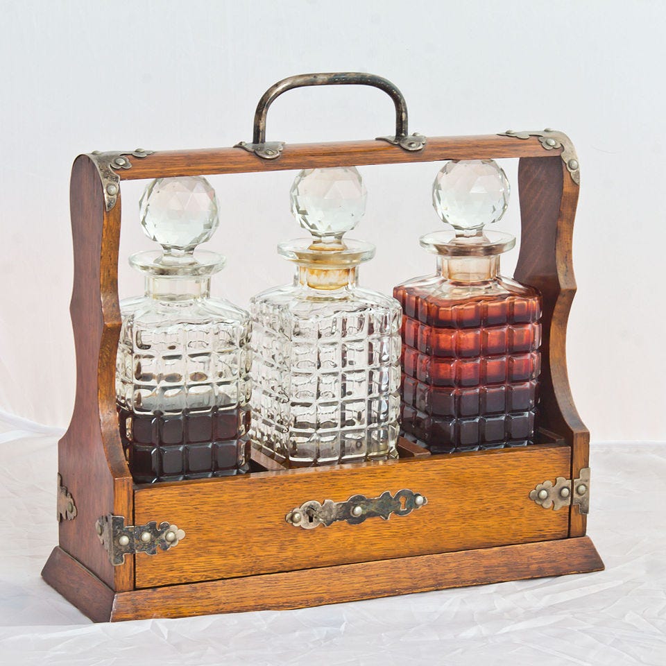 three glass bottles of alcohol in a wooden container that allows you to see the bottles, but not pull them out without the key