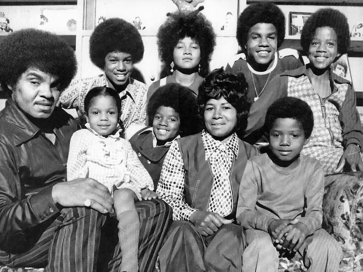 This may contain: the jackson family poses for a portrait in their living room This may contain: the jackson family poses for a portrait in their living room