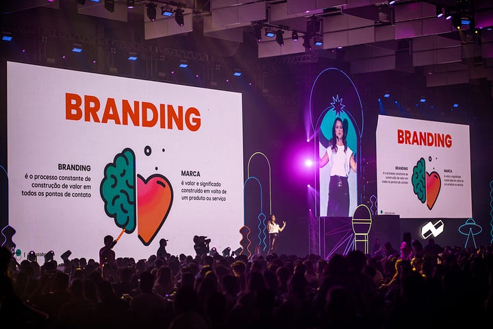três fotos da Beatriz em cima do palco do RD Summit, usando uma camiseta branca e uma saia de brilhos. duas delas de perto, a outra de longe, com dimensão do palco grande e um slide com a definição de branding atrás dela