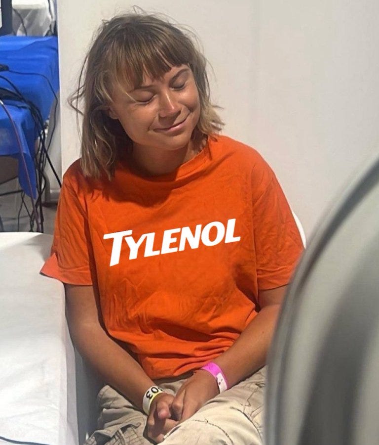 A person with shoulder-length hair wearing an orange Tylenol T-shirt and light-colored pants, sitting with hands clasped. A wristband is visible on their wrist.