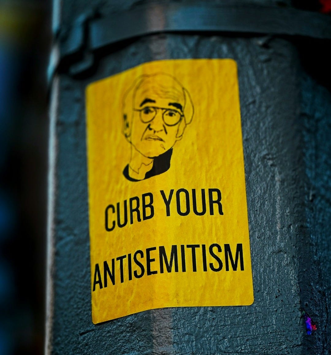 a sticker on the side of a pole that says curb your antisemit