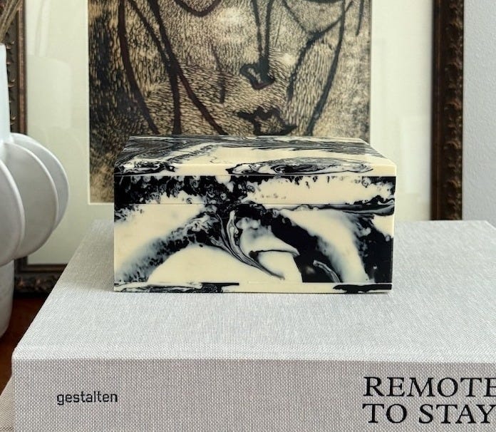 May include: A rectangular box featuring a marbled pattern of black and cream white swirls. The box has a smooth, polished finish and a lid that sits flush with the base. The swirling design creates a unique, fluid aesthetic across all visible sides.