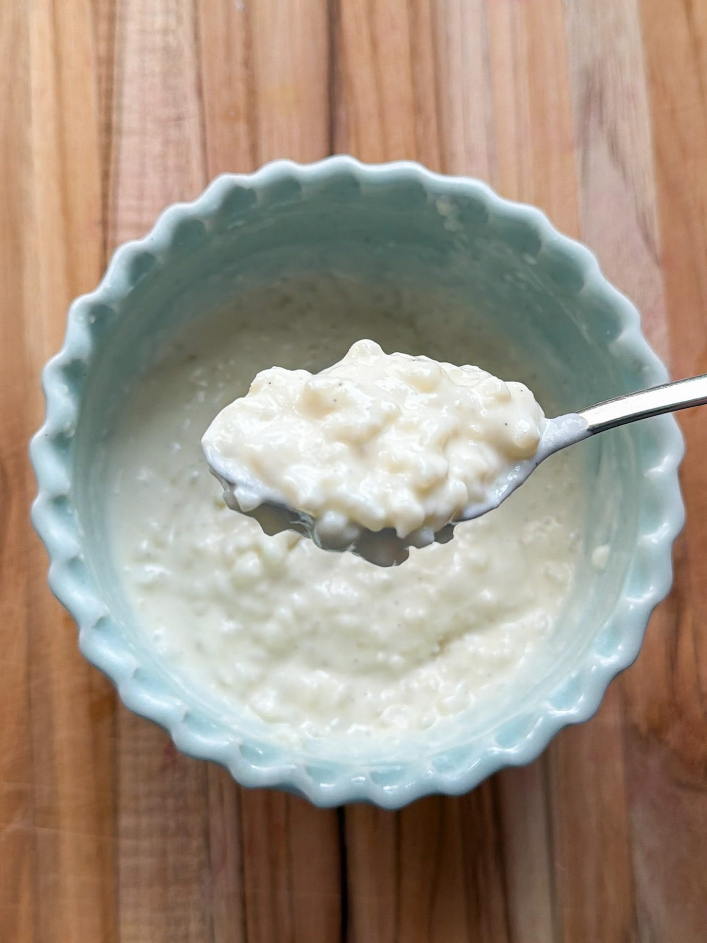 A spoonful of rice pudding over a bowl of rice pudding. A spoonful of rice pudding over a bowl of rice pudding.