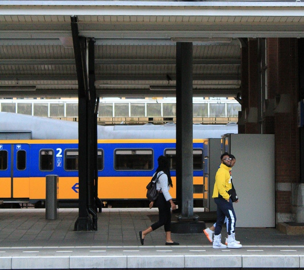 two persons walking beside train rail