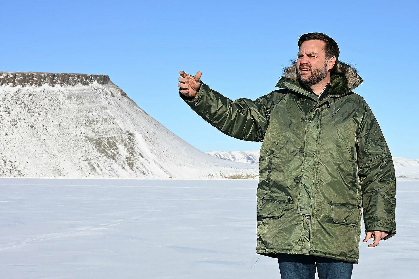 J.D. Vance on a barren snowscape gesturing at someone off camera.