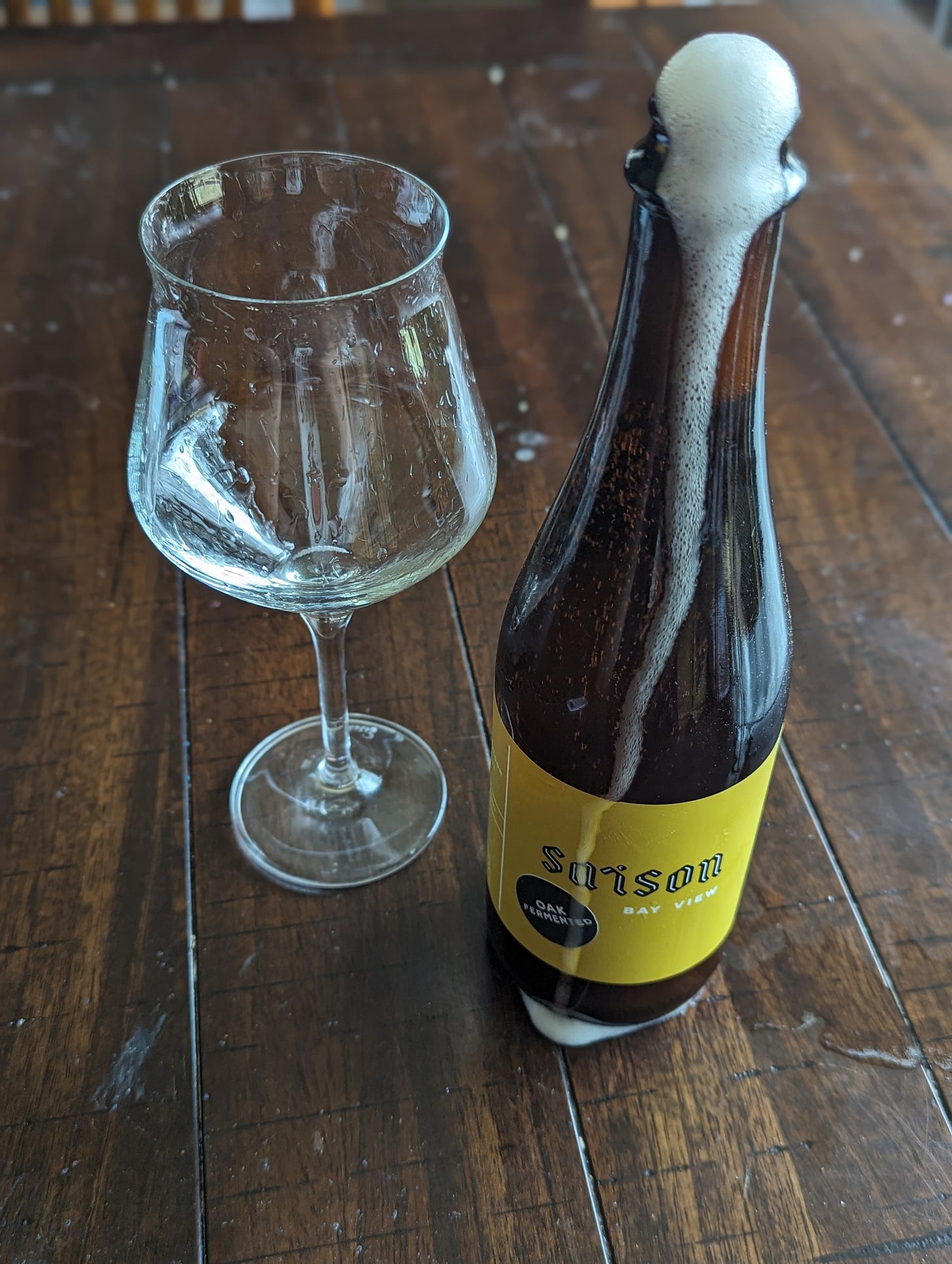 A large bottle with a light, white foam pouring itself out of the top of the bottle. A large bottle with a light, white foam pouring itself out of the top of the bottle.