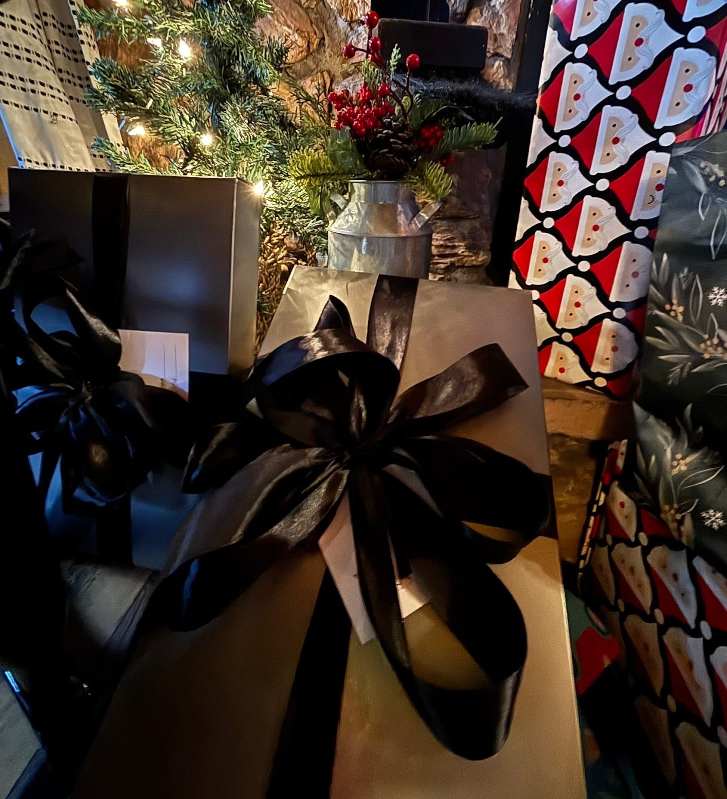 grey Nordstrom boxes with black ribbon under a lit tree with other presents