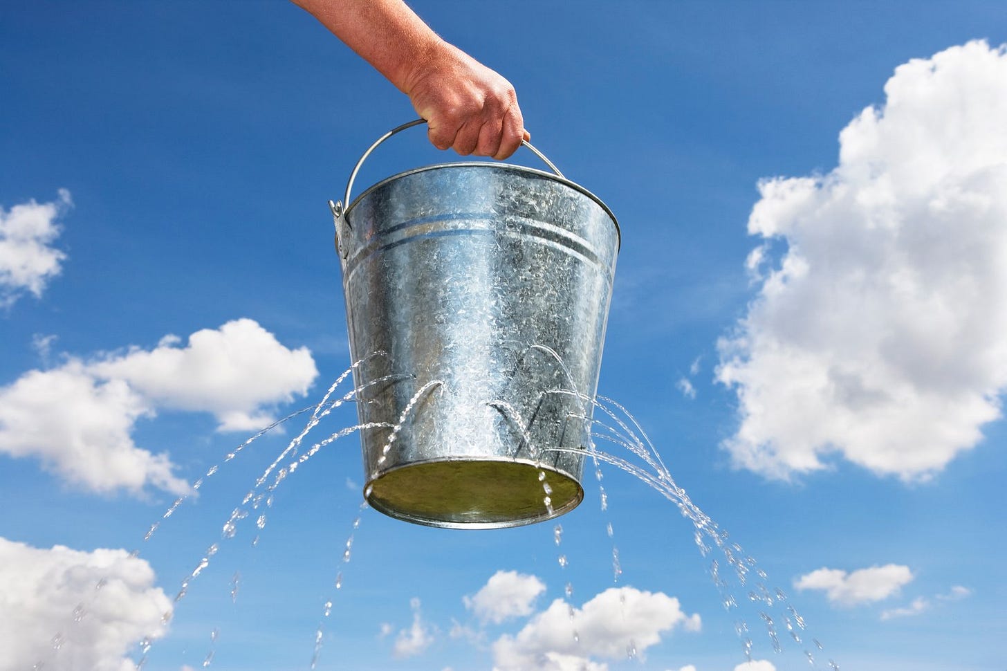A bucket with holes leaking water