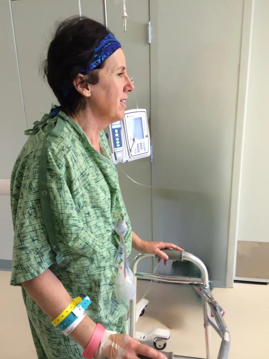 A woman patient uses a walker to walk the hospital hallway after having a double mastectomy.