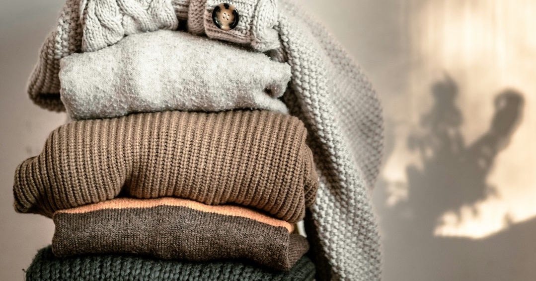 a stack of sweaters sitting on top of a wooden chair