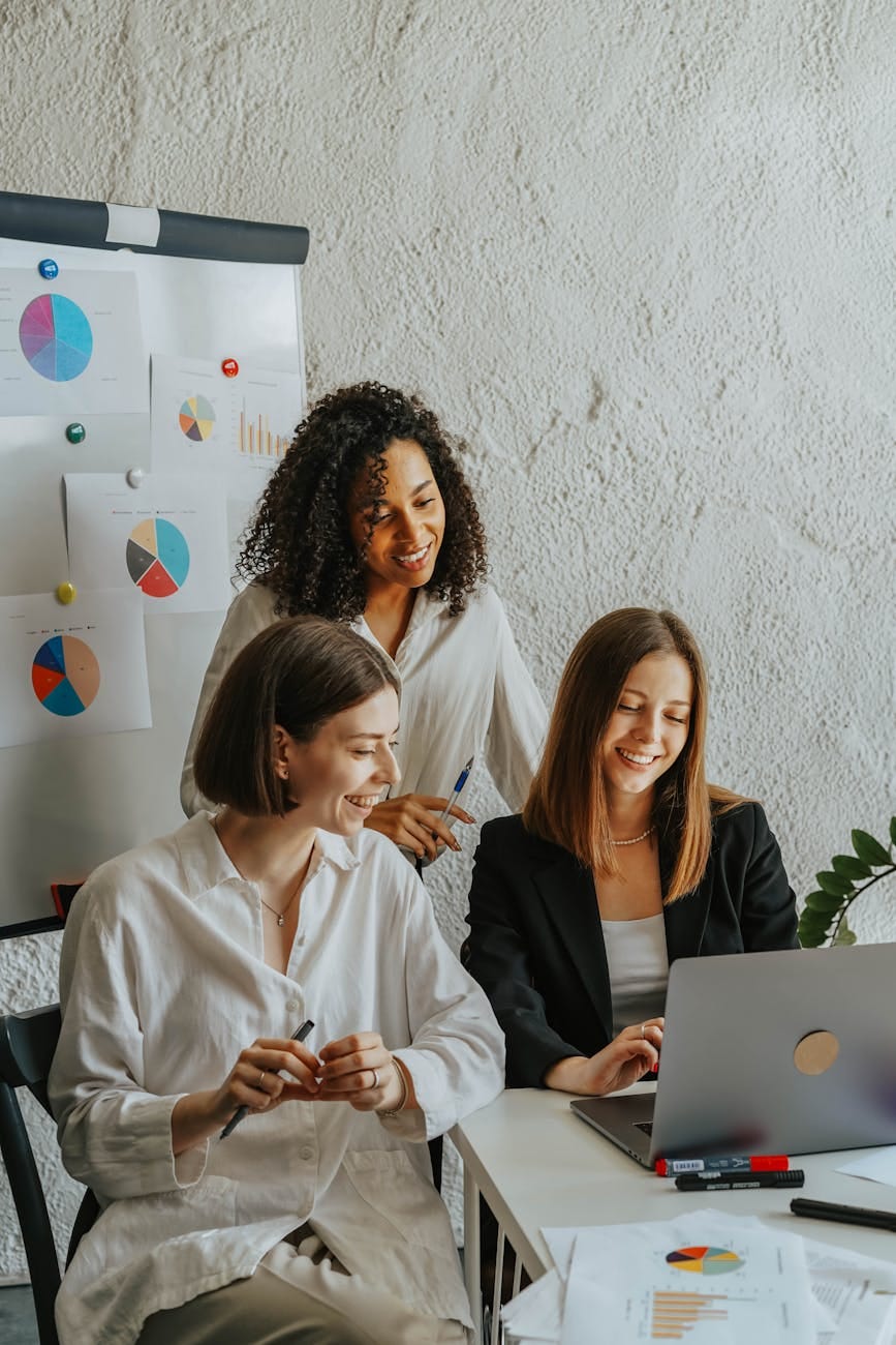 women in the office looking at laptop screen smiling