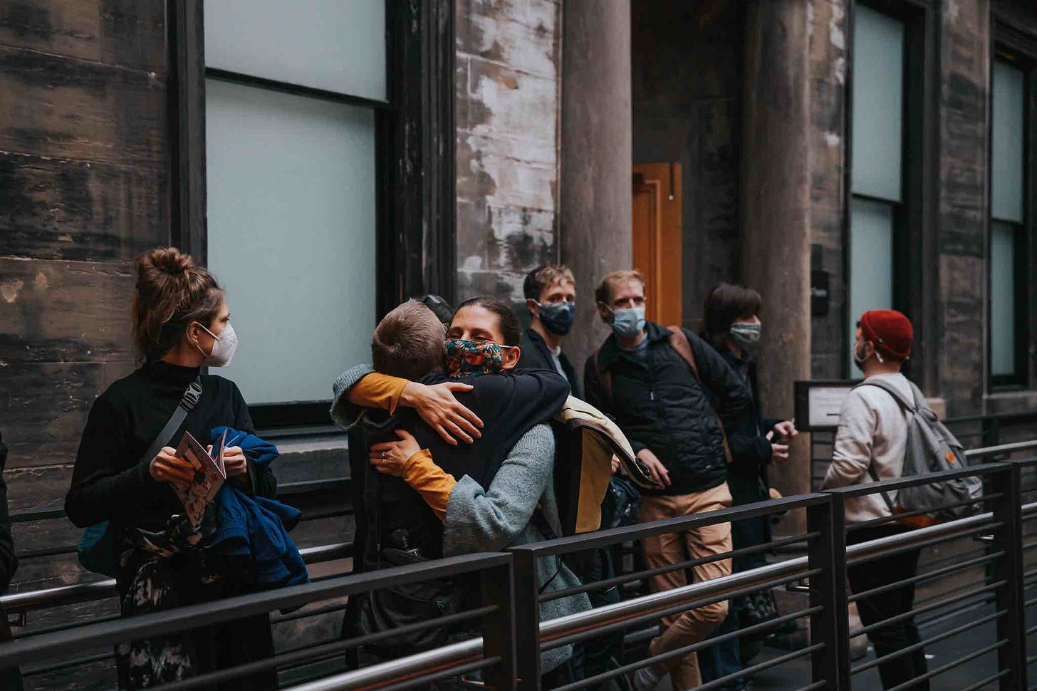 A handful of people wearing masks gather on the second floor of the CCA. Two are hugging each other. A handful of people wearing masks gather on the second floor of the CCA. Two are hugging each other.