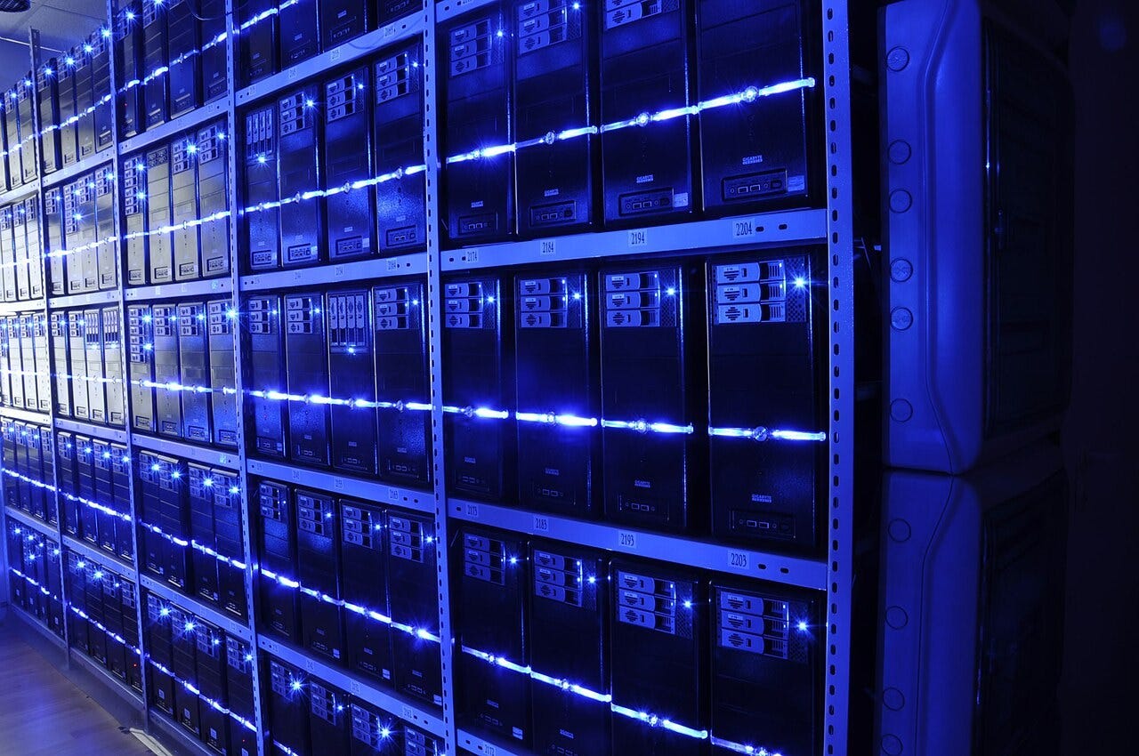 A data center server room with rows of computing equipment. A data center server room with rows of computing equipment.