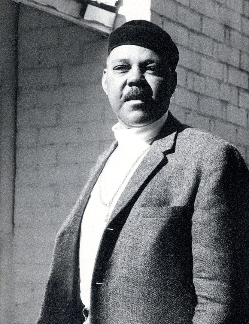 A black and white photo of a middle-aged Black man standing in bright sunlight
