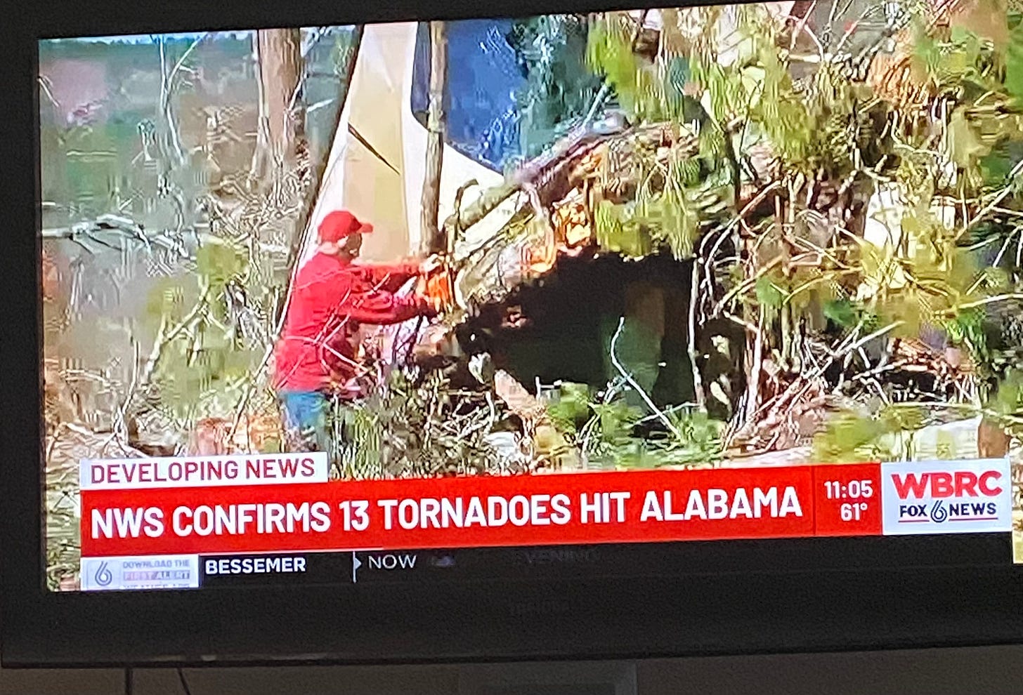 A photo of the TV screen reporting the news on March 19th, 2025 that "NWS confirms 13 tornadoes hit Alabama"