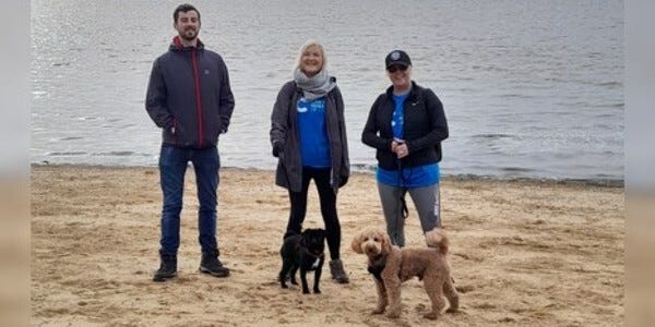 Three people and two dogs on a beach