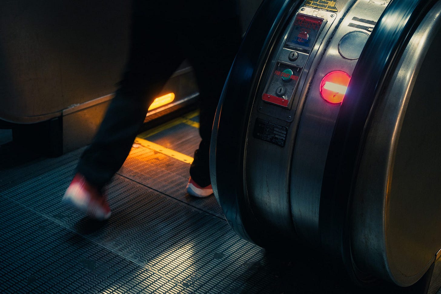 A close-up of a a person’s legs as they step onto an escalator.