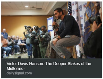 The image depicts Victor Davis Hanson speaking at a podium, likely in a conference or public forum, surrounded by an audience and media coverage. AI-generated content may be incorrect.