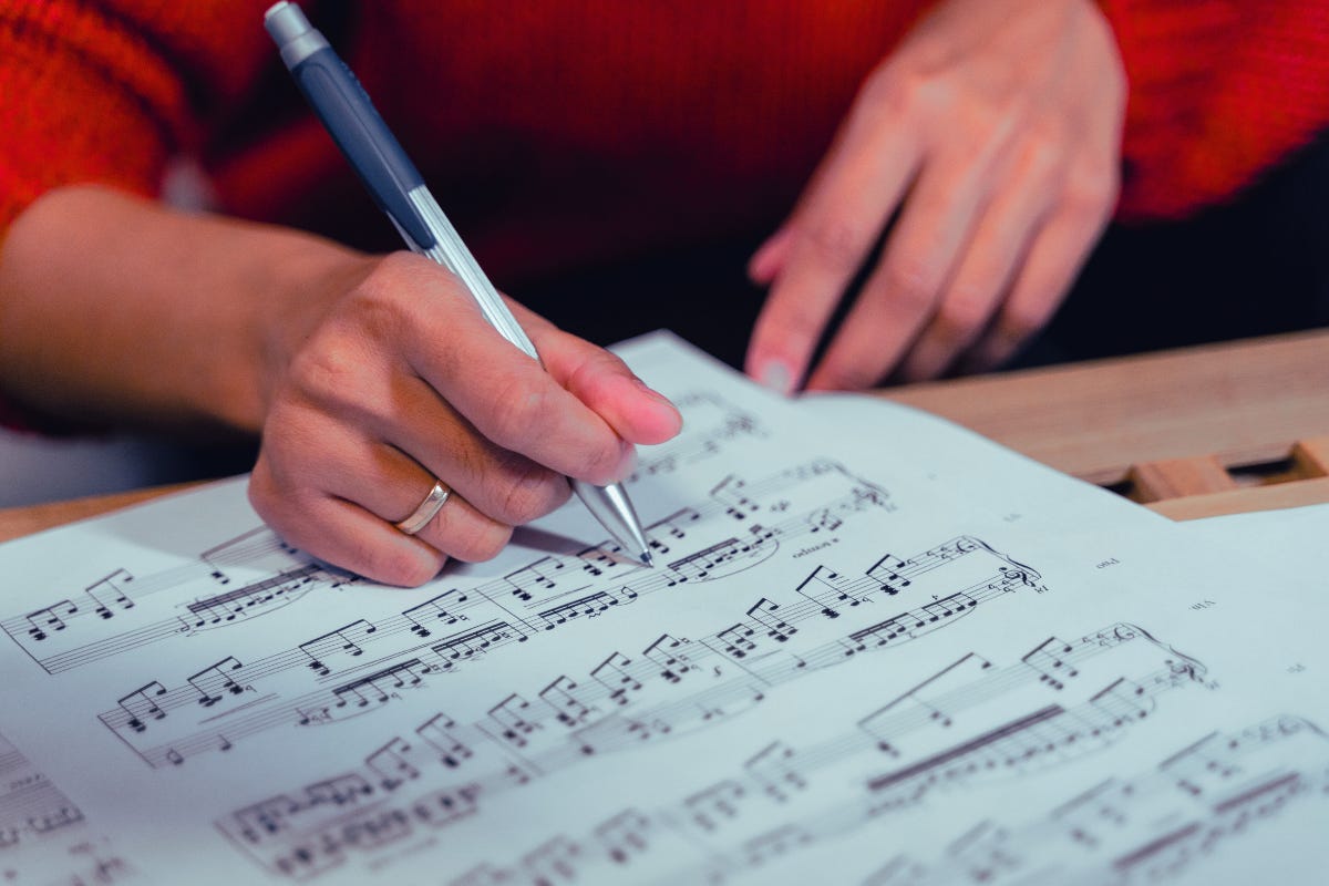 Close up of a woman's hands writing sheet music. Close up of a woman's hands writing sheet music.