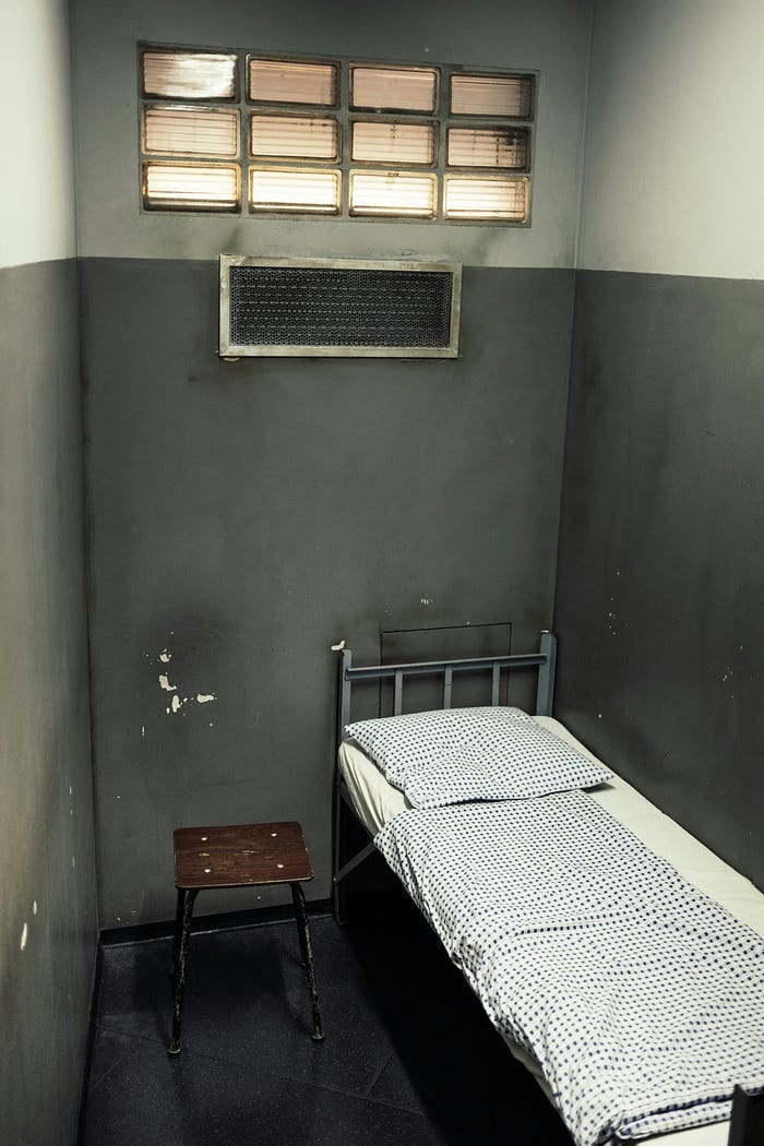A tiny prison cell with a single bed. A tiny prison cell with a single bed.