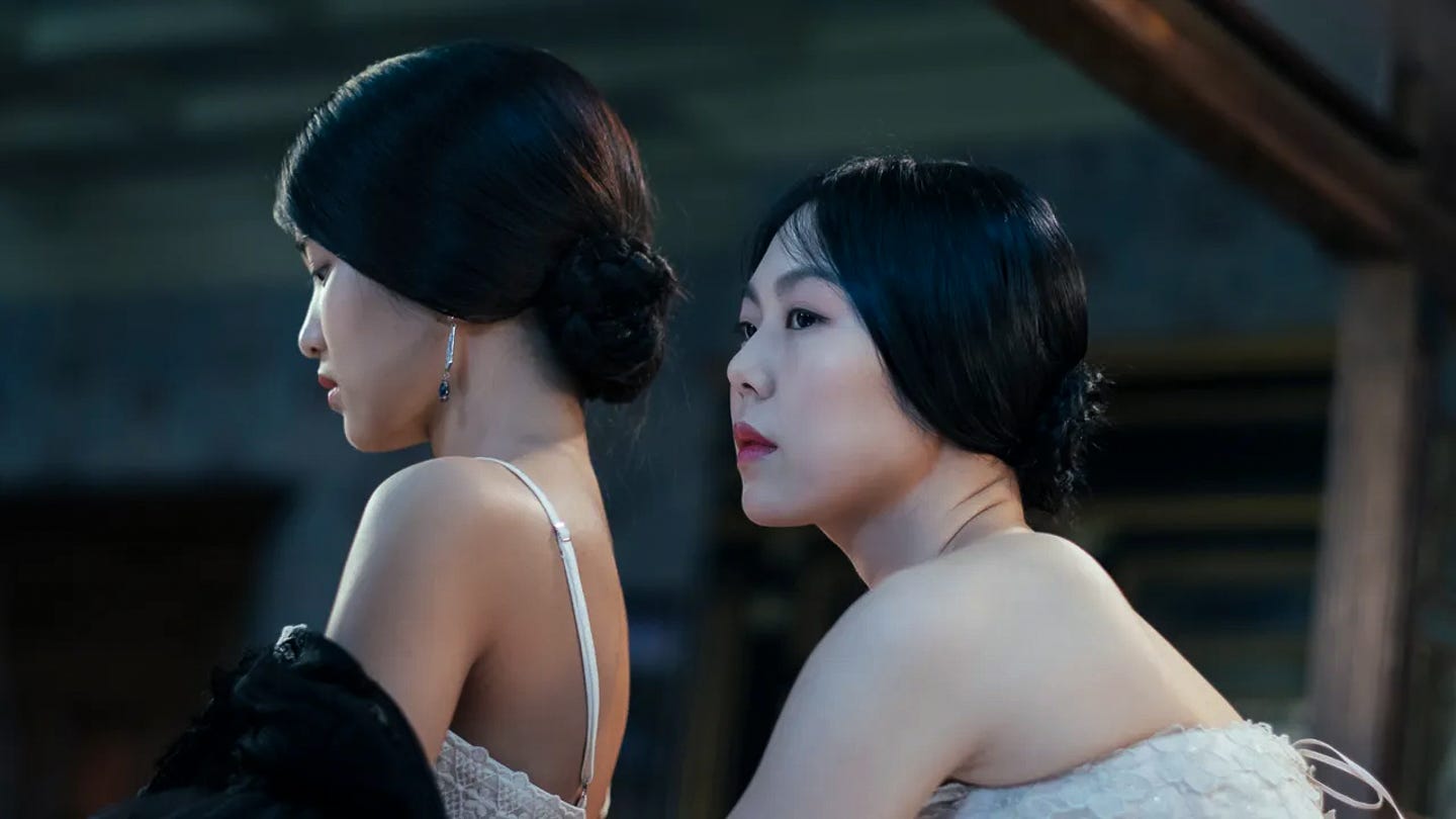 Two women in corsets, one behind the other, their faces close but facing the same direction with one peering off to the side. Intimate lighting and rich textures suggest both eroticism and unease. Two women in corsets, one behind the other, their faces close but facing the same direction with one peering off to the side. Intimate lighting and rich textures suggest both eroticism and unease.