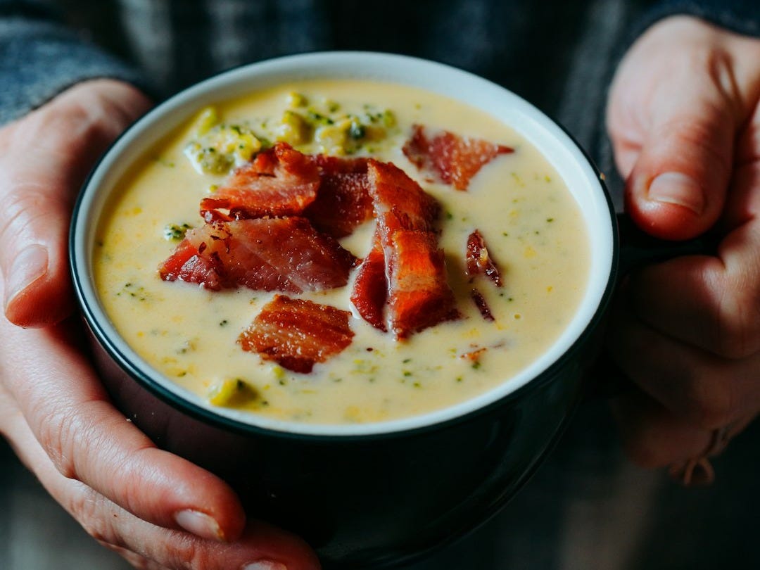 person holding white ceramic bowl with soup