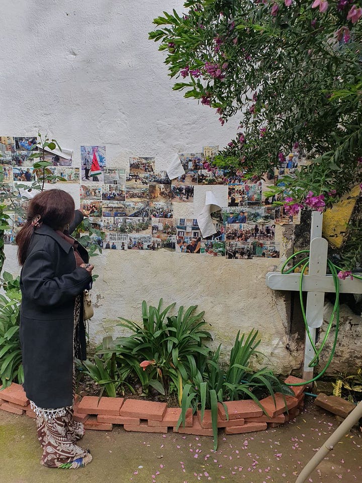 A woman is pointing at a wall with many fotos, next to her are plants and a garden hose. The other image shows a poster with a person cuddling a dog, it says: Juan Andrés Benítez, ni olvido ni perdon.