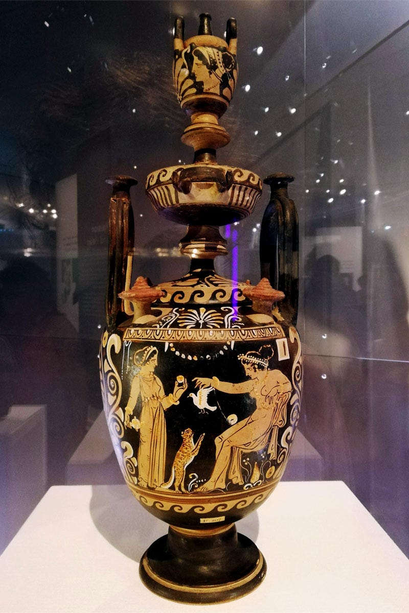 An intricate ancient vase in black and orange inlcuding images of two women and a cat
