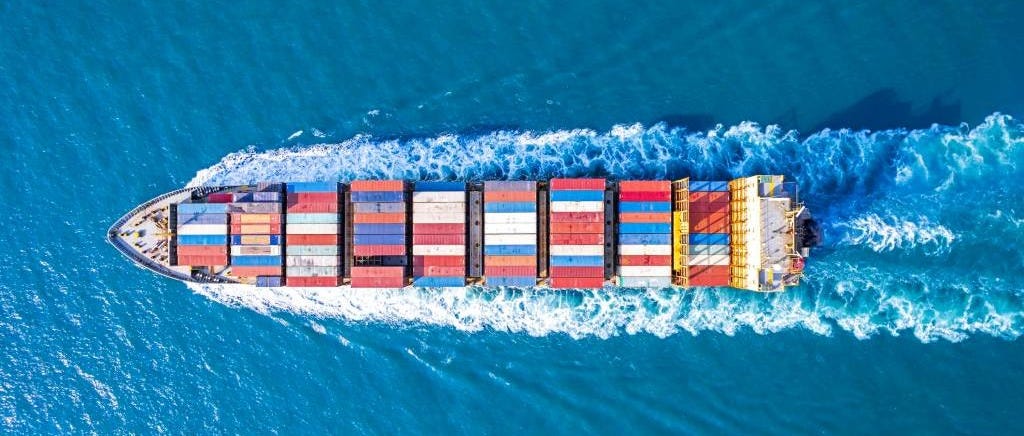 overhead shot as cargo ship sails on a blue sea.