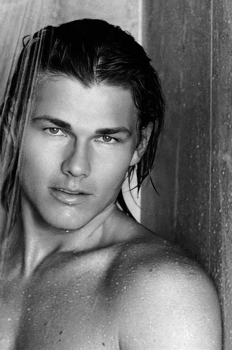 Wet-haired person in a shower, water cascading down. Black and white image with a serene expression, tiled wall background.