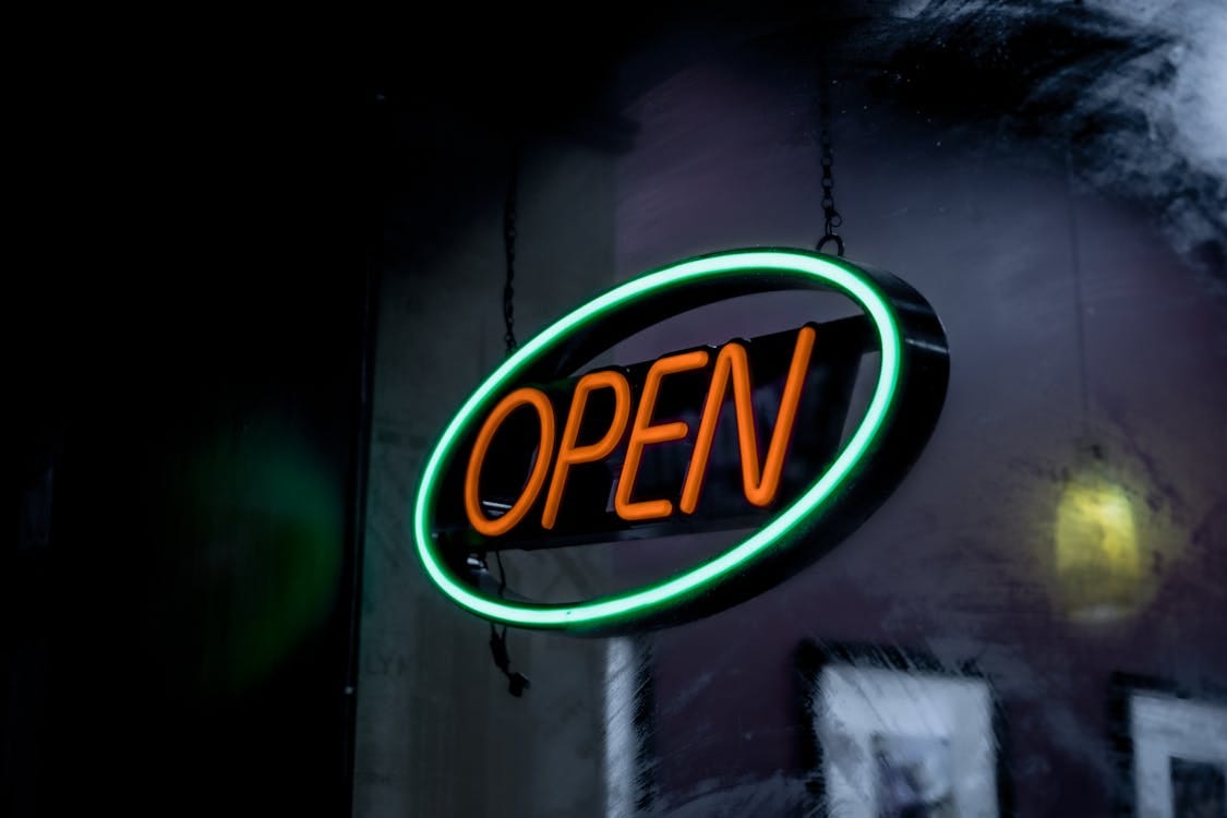 Free Vibrant neon open sign glowing in a dimly lit setting, creating a welcoming ambiance. Stock Photo