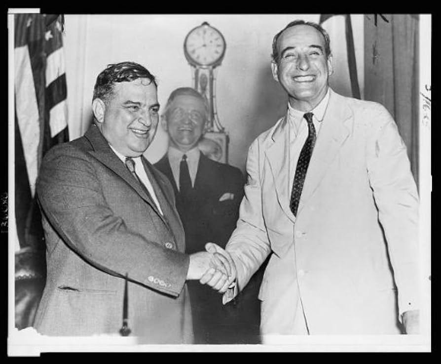 Robert Moses is really hamming it up, shacking hands with Fiorello LaGuardia. LaGuardia is quote short.