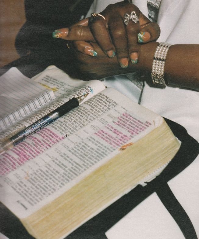This may contain: a woman sitting in front of an open bible