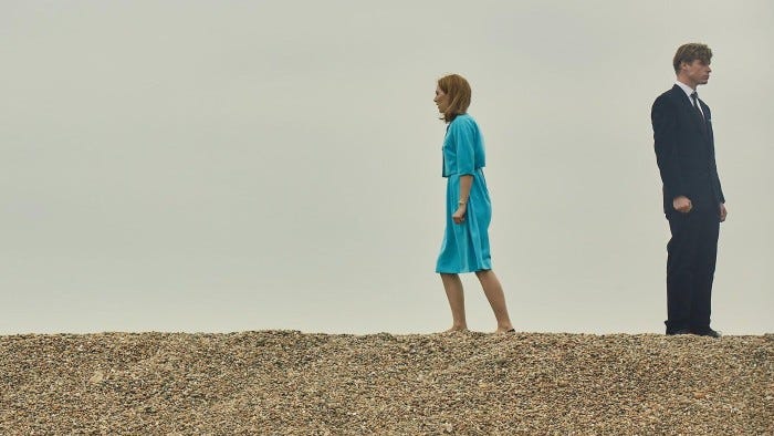 On a pebble beach, a young woman walks away from a man On a pebble beach, a young woman walks away from a man