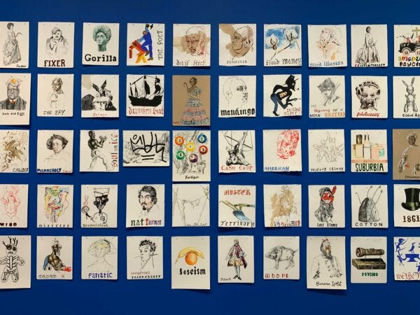 A gallery installation featuring many small artworks hung on top of a royal blue-painted wall.