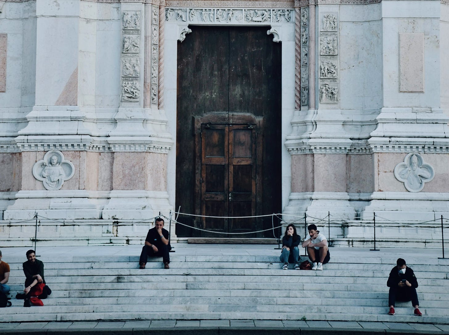People sitting outside the Basilica of San Petronio in Bologna, Italy