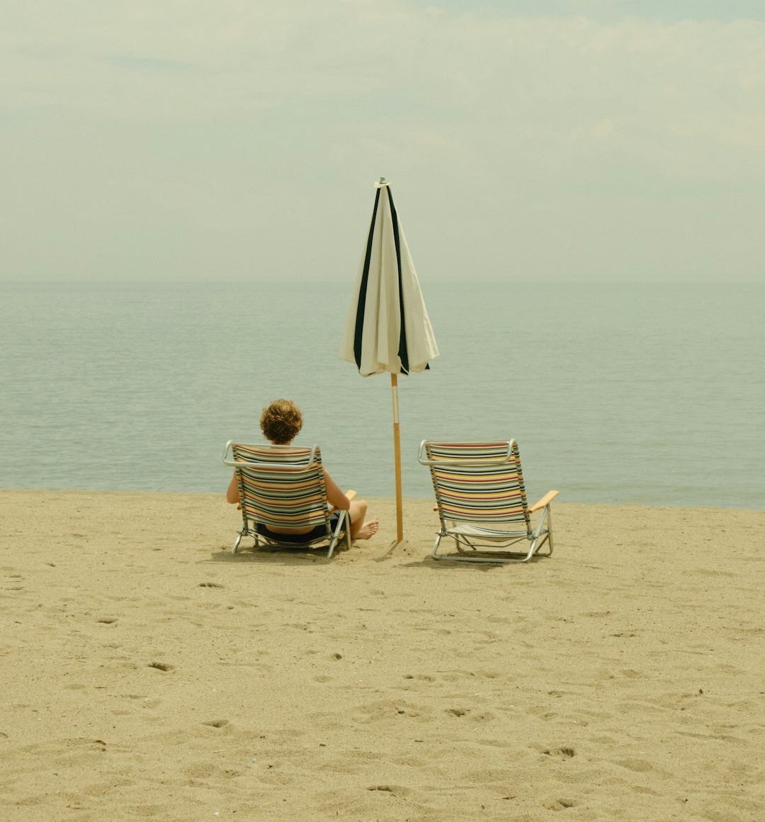 a person sitting on a beach under an umbrella