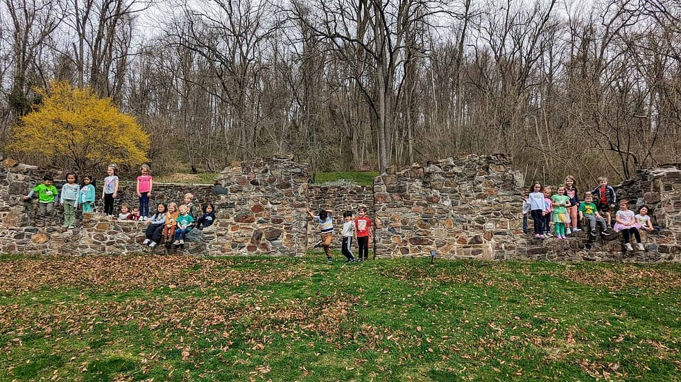 A group of youth programs participants pose in front of the preserved structure while touring the grounds of historic yellow sprigns