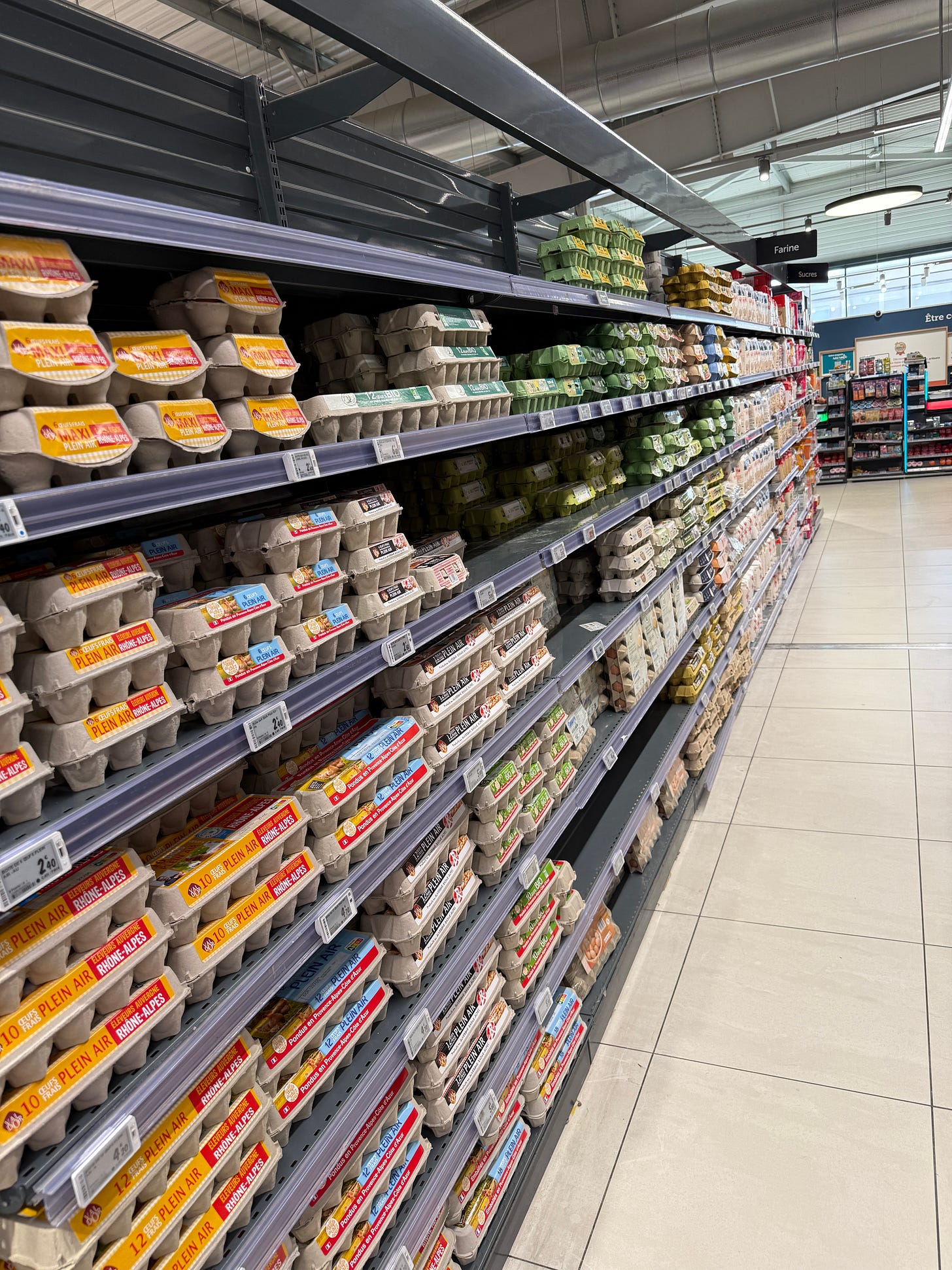 An image depicting a long supermarket aisle with shelf after shelf of room-temperature egg cartons. An image depicting a long supermarket aisle with shelf after shelf of room-temperature egg cartons.