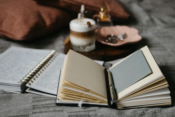 open journals with written pages, blank pages, pen, coffee, candles