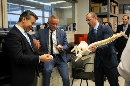 FDA Commissioner Dr. Martin A. Makary (left) and HHS Secretary Robert F. Kennedy Jr. (center) examine a model of a human spine in an FDA laboratory. (HHS Photo)