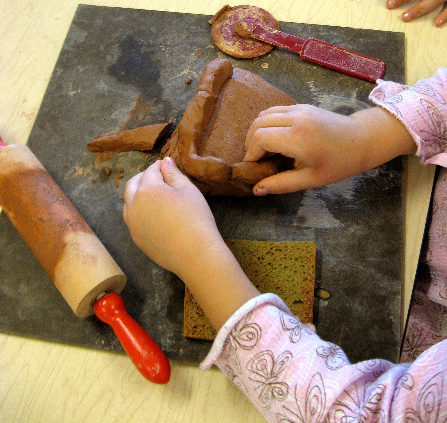 image of the hands of a child as she works with clay
