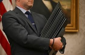 man holding stack of leather folders with exectuive orders in them