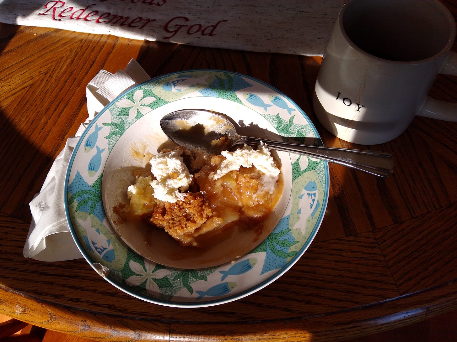 Bowl of apple crisp, with something that looks like ice cream, and a mug that says Joy nearby Bowl of apple crisp, with something that looks like ice cream, and a mug that says Joy nearby