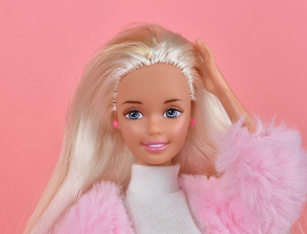A barbie doll with blonde hair and pink pants